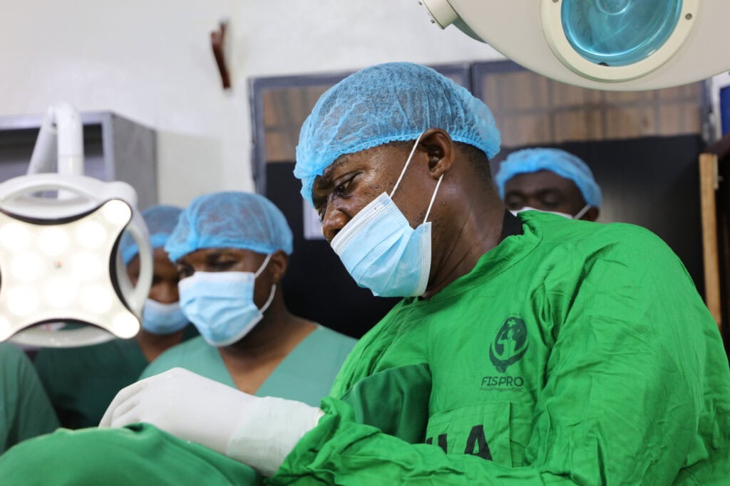 A surgeon in scrubs operates on a patient